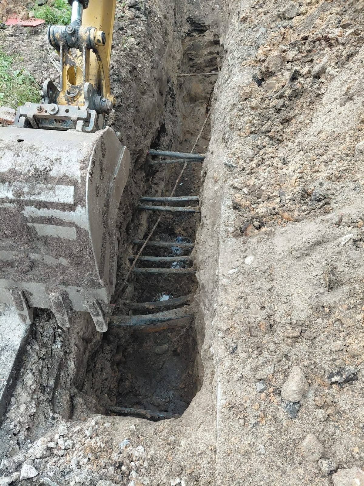 Tranšeja, kuru šķērso daudzas esošās caurules un kabeļi